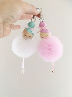 two small keychains are being held up by someone's hand and the other one is wearing a pink ballerina