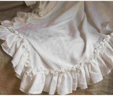 a white dress with ruffles is laying on the floor next to a pillow