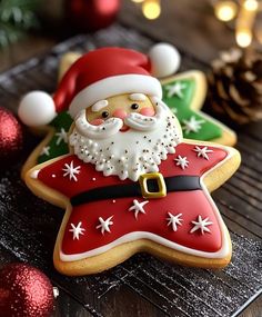 christmas cookies decorated like santa claus and snowflakes with pine cones in the background