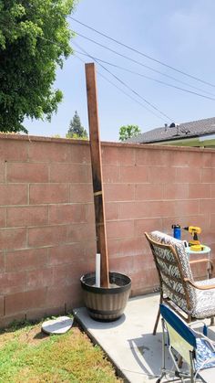 a chair and table in front of a brick wall with a wooden pole sticking out of it