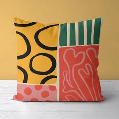 a colorful pillow sitting on top of a white table next to a yellow and red wall