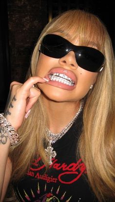 a woman wearing sunglasses and holding her finger to her mouth