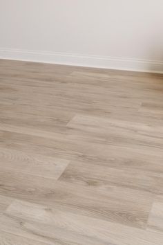 an empty room with white walls and wood flooring on the ground, in front of a chair