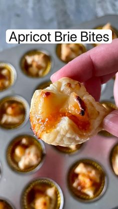 a hand holding up a piece of food in front of some muffin tins