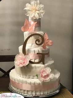 a three tiered wedding cake with pink and white flowers on the top, sitting on a table