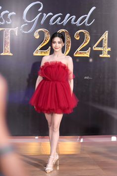 a woman in a red dress is walking down the runway