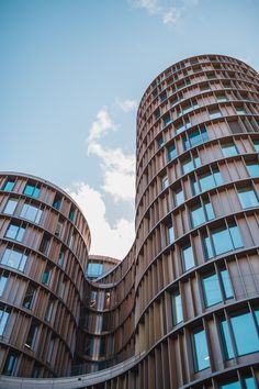 two tall buildings with curved windows against a blue sky and white clouds in the background