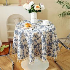 a table topped with a white vase filled with flowers next to a cup and saucer