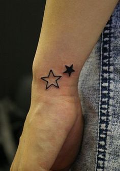 a woman's hand with a small black star tattoo on her left inner wrist