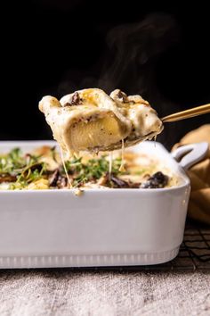 a spoonful of food is being lifted from a casserole in a white dish