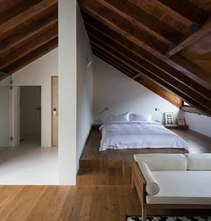 an attic bedroom with white bedding and wooden floors