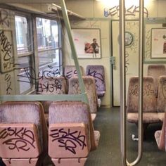 the seats are covered in graffiti on the subway car's side rails and walls