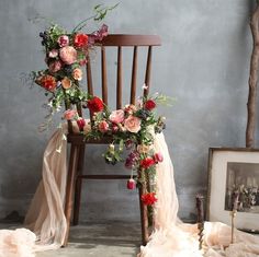 a chair decorated with flowers and greenery next to an old photograph on the floor