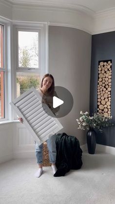 a woman standing in front of a window next to a pile of luggage and a large piece of wood