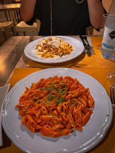 a woman taking a photo of her plate of pasta and macaroni on the table