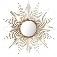 a gold sunburst mirror hanging on the wall in front of a white background