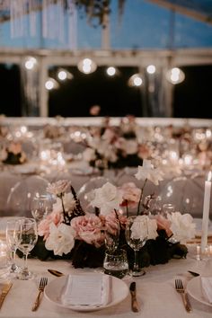 the table is set with white and pink flowers, silverware, and wine glasses