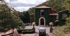 a car is parked in front of a house with ivy growing on it's walls