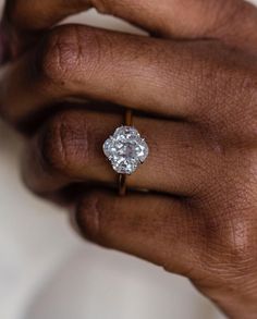 a close up of a person's hand holding a diamond ring