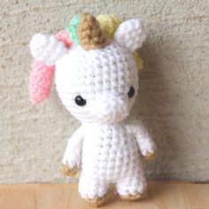 a small crocheted stuffed animal with a bow on its head sitting against a wall