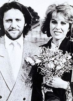 two people standing next to each other holding flowers