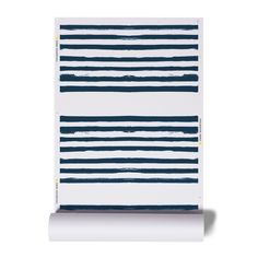 a blue and white striped wall hanging on the side of a building with a roll of paper in front of it