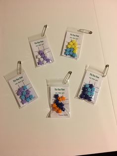 six different colored buttons in plastic bags on a white counter top with clippings