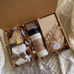 an open box with coffee, cookies and other items in it sitting on a blanket