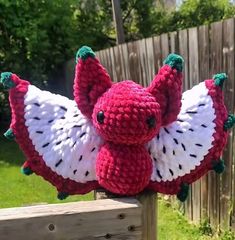 a crocheted stuffed animal hanging on a fence post