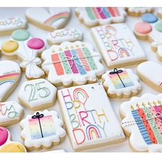 decorated cookies with happy birthday images and candles are displayed on a white tablecloth covered surface