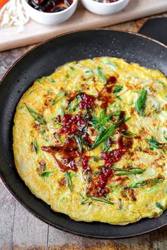 an omelet with green onions and cranberry sauce in a skillet