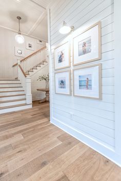 there are pictures hanging on the wall next to the stairs in this house with wood flooring