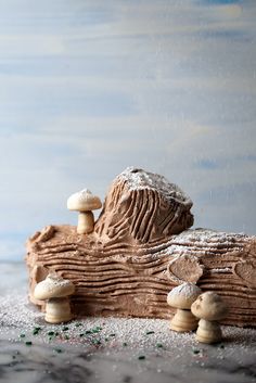 a piece of wood with mushrooms on it and snow falling over the top, in front of a blue background