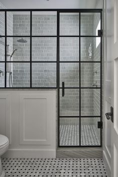 a white toilet sitting next to a shower in a bathroom with black and white tile