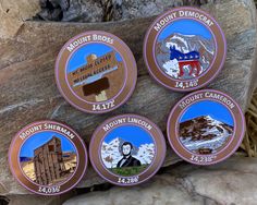 four badges are placed on a rock in front of some rocks and boulders with the name mount bros national historic landmark