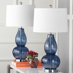 two blue vases sitting on top of a table next to each other with a white lamp