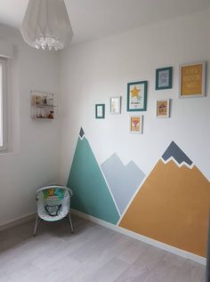 a baby's room with mountains painted on the wall and a rocking chair next to it