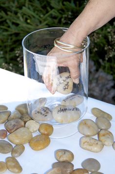 a person's hand reaching into a glass filled with rocks