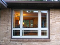 an open window on the side of a brick building with glass panes in it