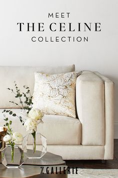 a white couch sitting next to a table on top of a hard wood floored floor