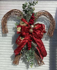 a christmas decoration hanging on the side of a building with red bows and balls attached to it