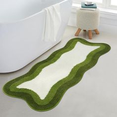 a bath tub sitting next to a green and white rug