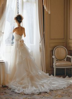 a woman in a wedding dress looking out the window