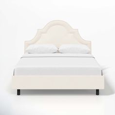 a bed with white linens and pillows on top of the headboard is shown