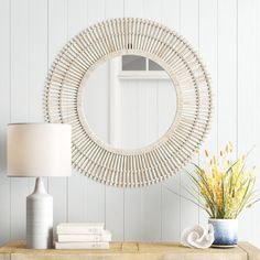 a table with a lamp, vase and mirror on it next to a white wall