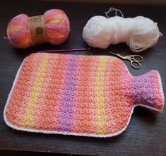 a crocheted dishcloth, yarn and scissors on a table