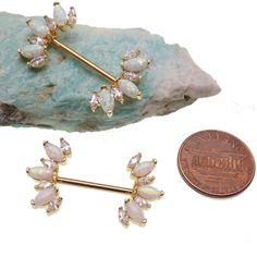 a pair of opalite and diamond ear studs next to a penny on a white background