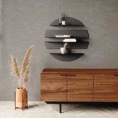 a wooden cabinet and vase in a room with grey walls, white flooring and a circular mirror on the wall above it