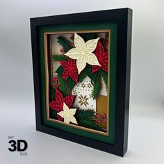 an origami christmas decoration in a shadow box with holly and poinsettis