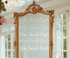 a mirror with writing on it in front of a chandelier filled with flowers